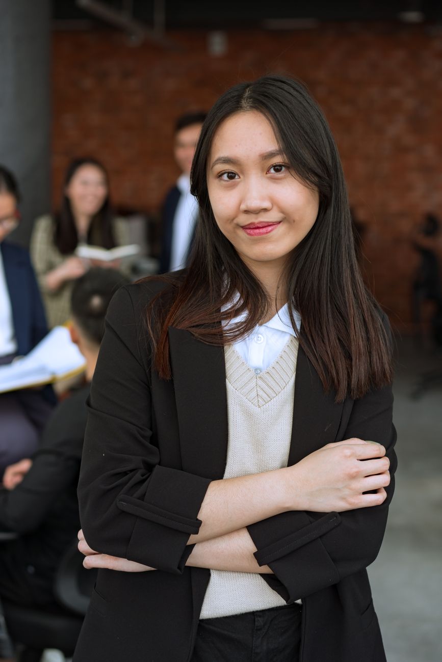 Potret wanita Asia tersenyum yakin berpakaian formal.